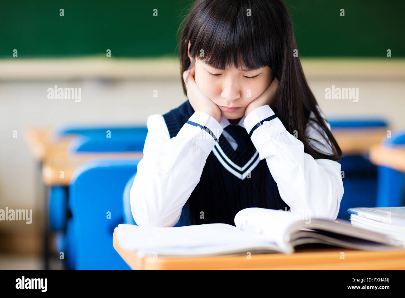 Stressed Student Of High School Sitting in classroom Stock Photo