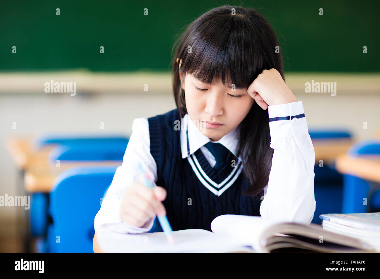 Stressed Student Of High School Sitting in classroom Stock Photo