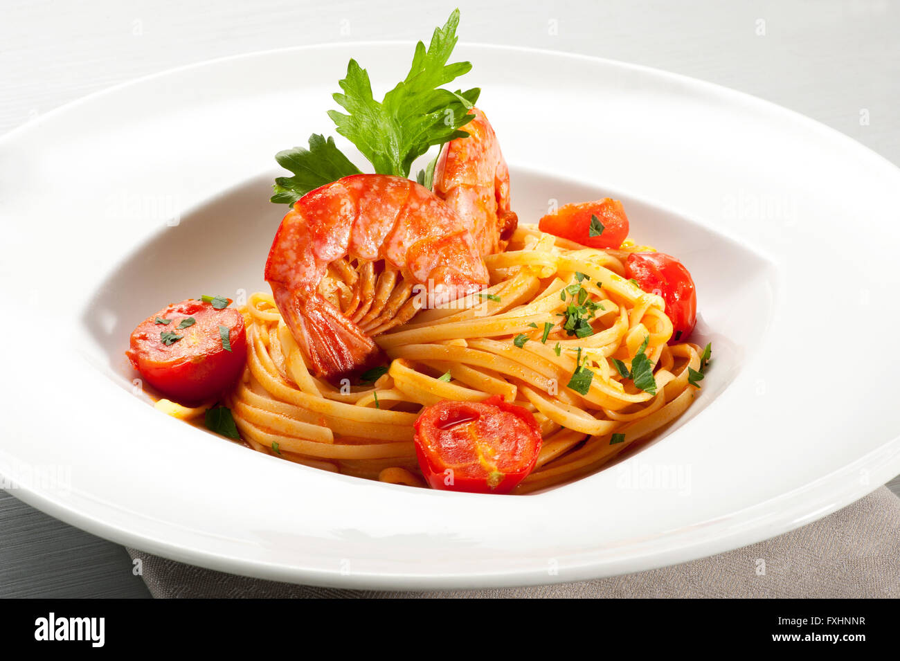 Single bowl serving of spaghetti noodles and prawns on top surrounded