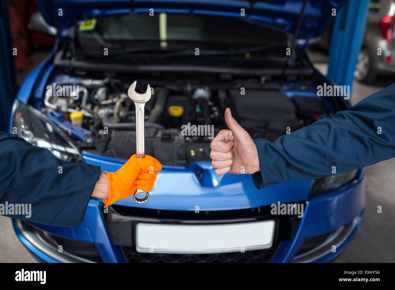 Mechanics holding spanner and showing thumbs up Stock Photo - Alamy