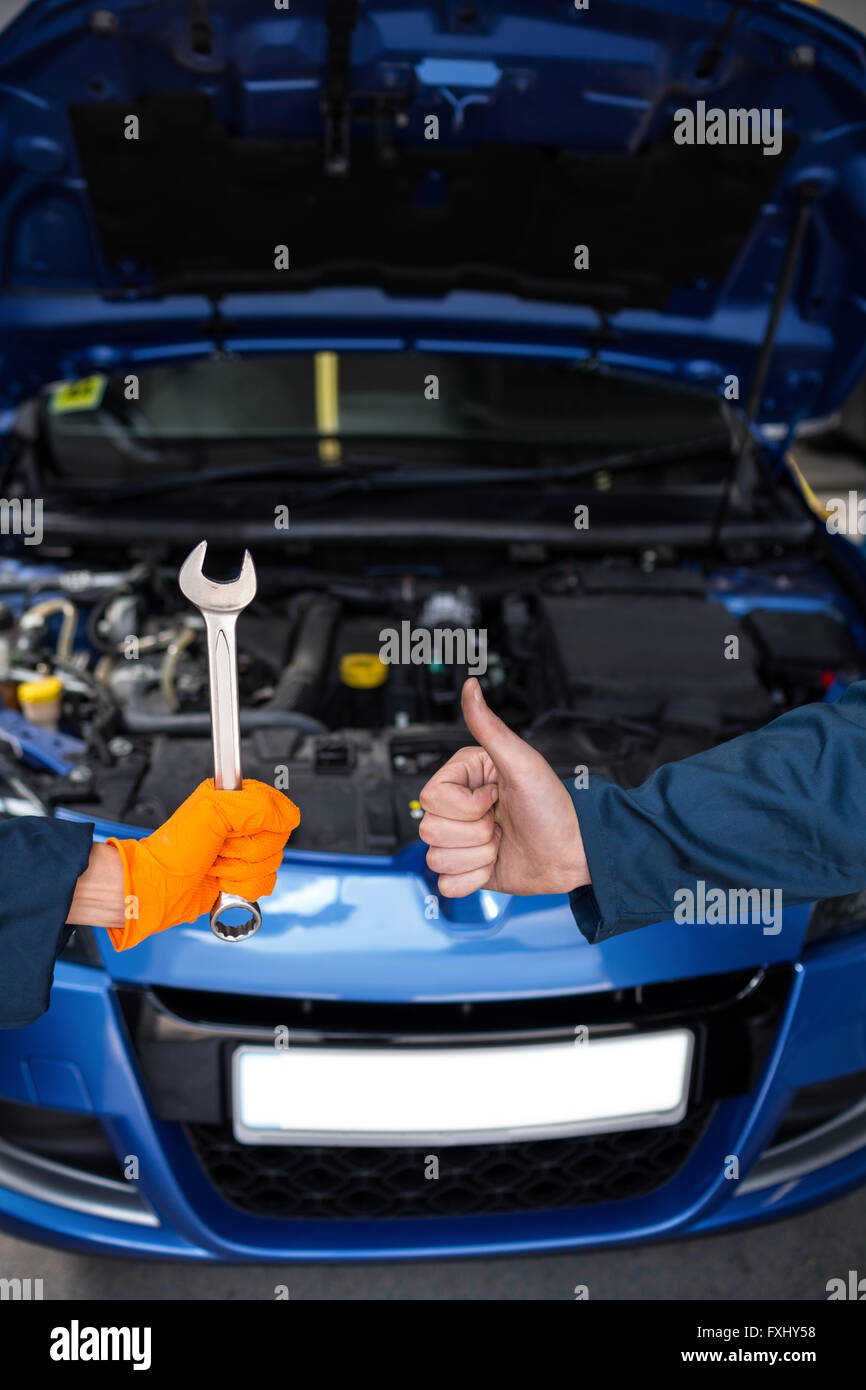 Mechanics holding spanner and showing thumbs up Stock Photo - Alamy