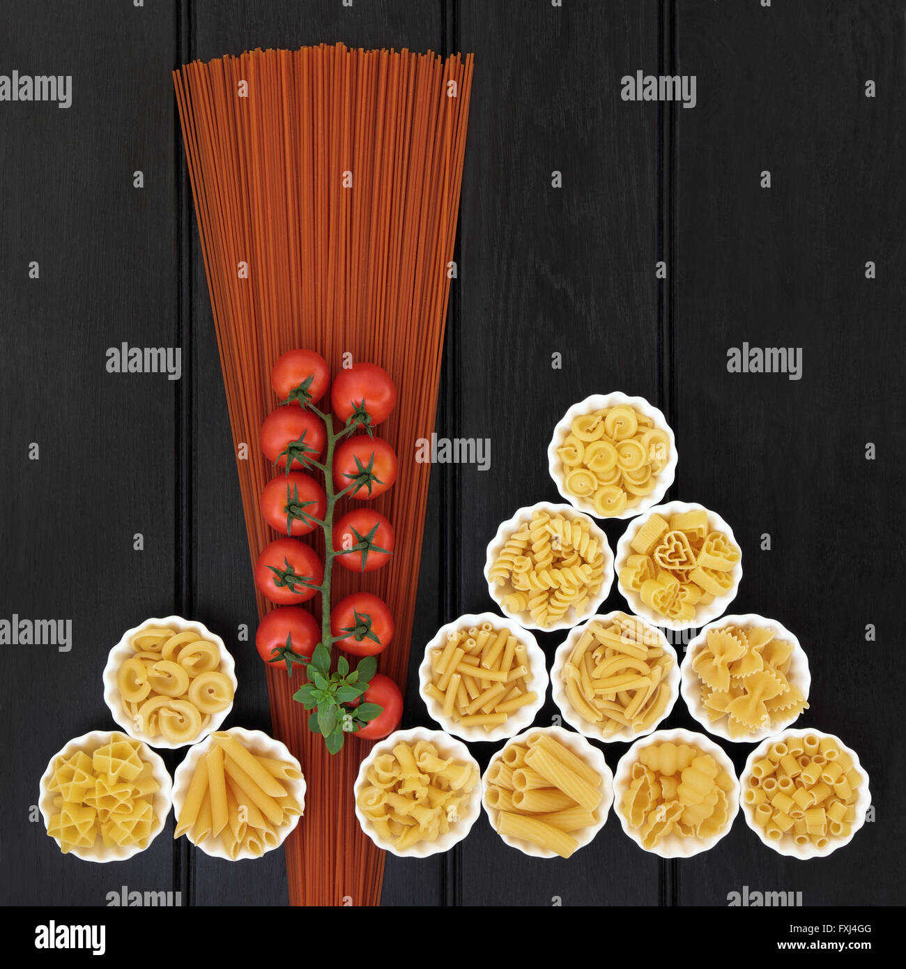 Tomato  spaghetti and italian pasta dried food selection in porcelain crinkle bowls over dark wood  background. Stock Photo