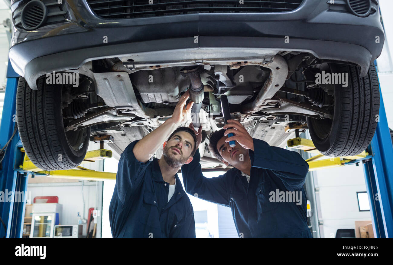 Mechanics examining silencer of a car using flashlight Stock Photo Alamy
