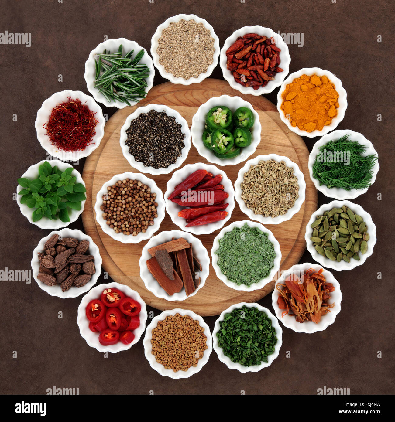 Large herb and spice selection in porcelain crinkle bowls on wooden board. Stock Photo