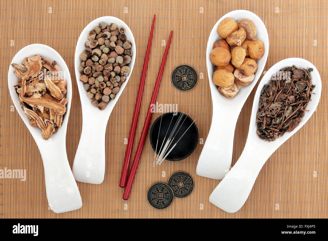 Acupuncture needles and chinese herbal medicine selection with chopsticks and I ching coins over bamboo background. Stock Photo