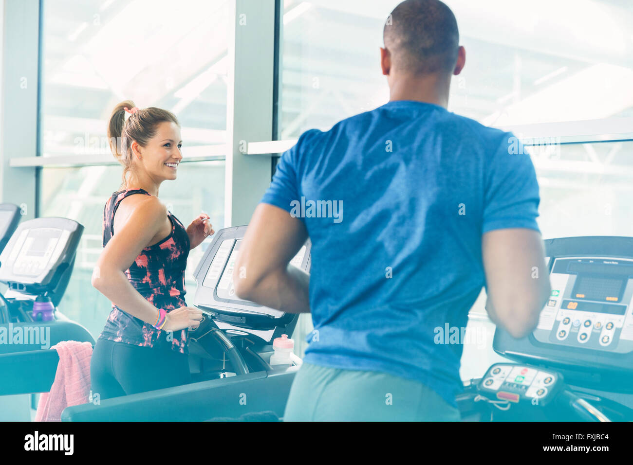 Man and woman jogging on treadmills at gym Stock Photo