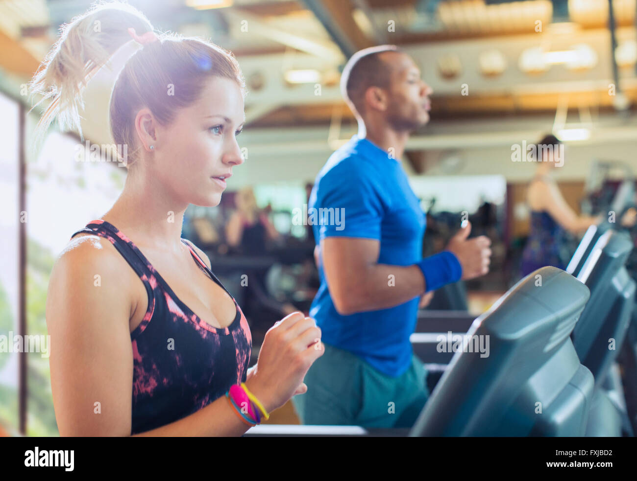 Focused woman running on treadmill at gym Stock Photo