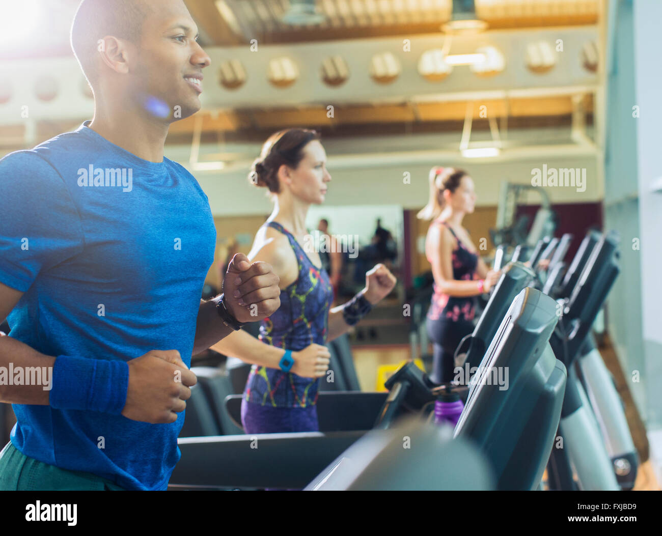 Smiling man running on treadmill at gym Stock Photo