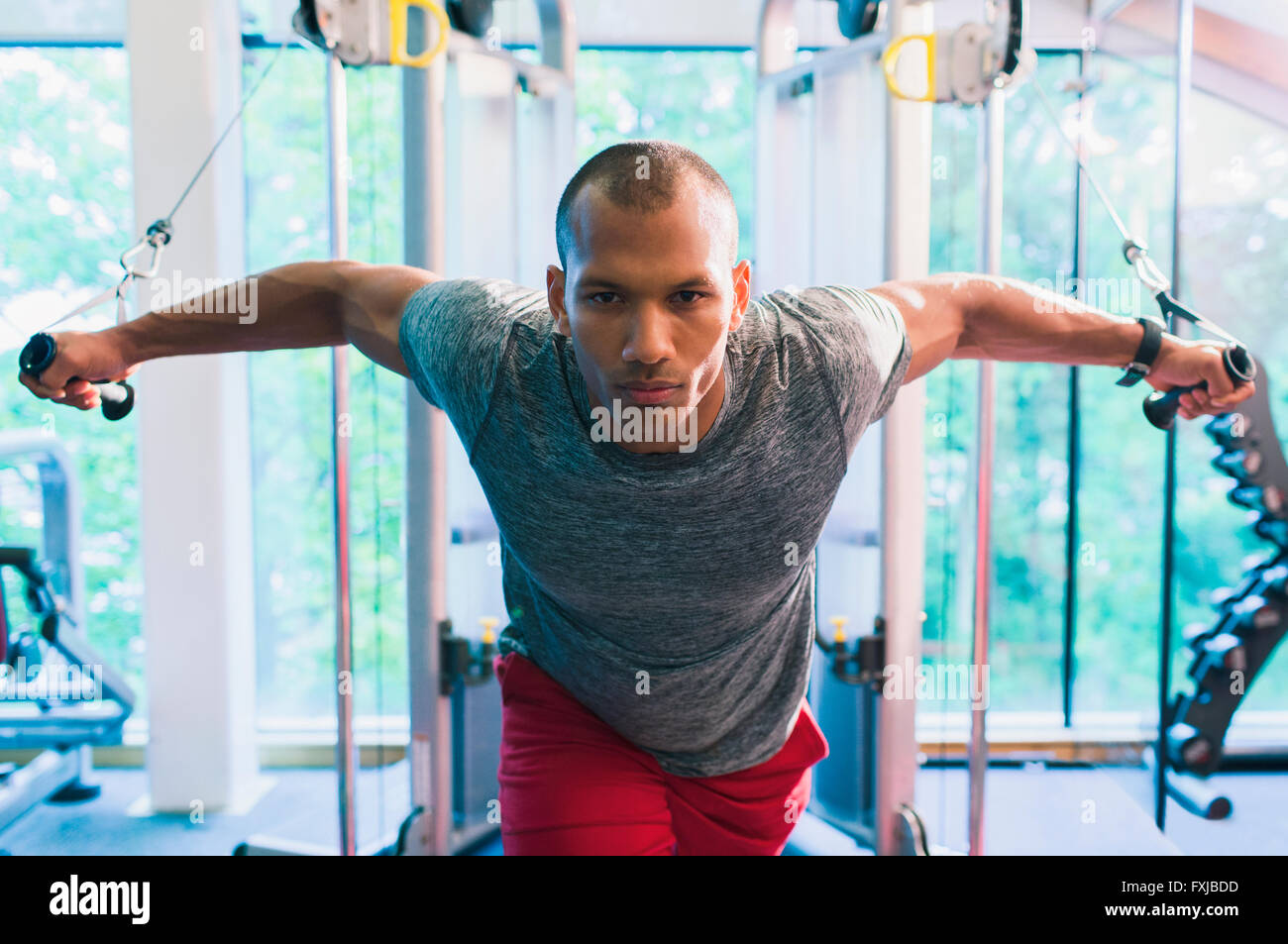 Determined man doing cable chest fly at gym Stock Photo