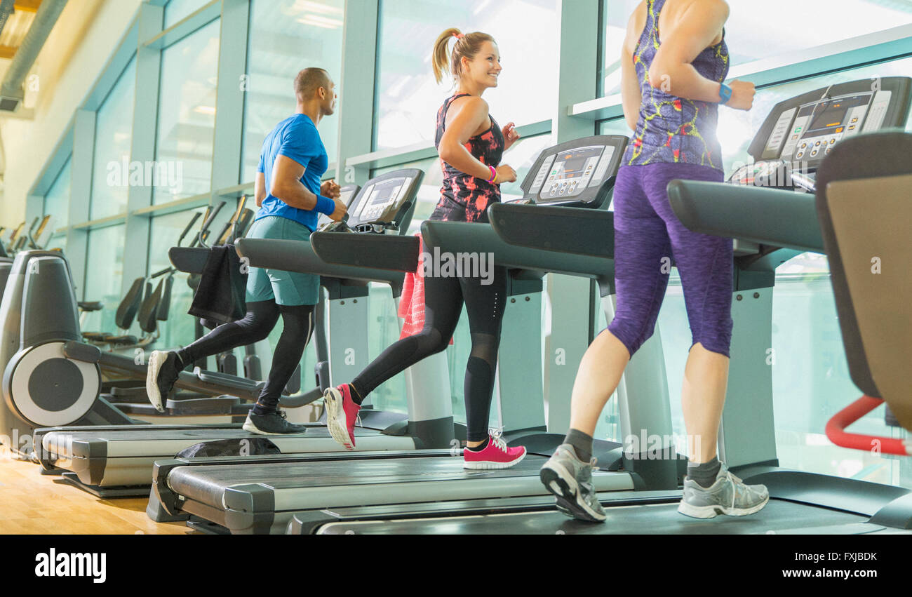 Man and women running on treadmills at gym Stock Photo
