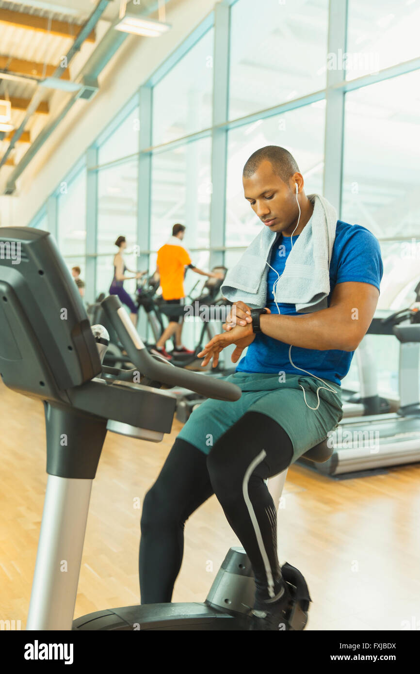 Man checking smart watch on exercise bike at gym Stock Photo - Alamy