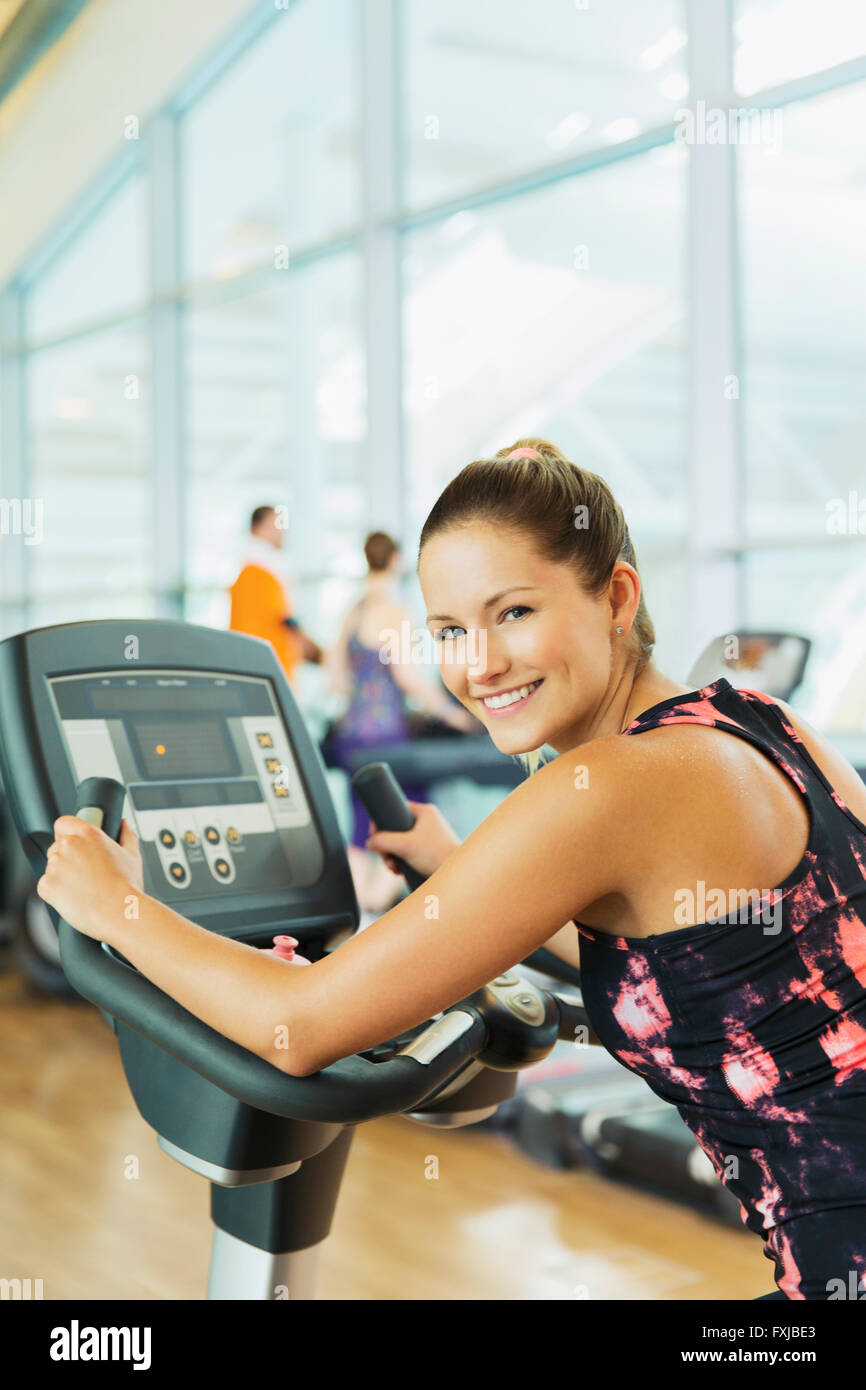 Portrait smiling woman on exercise bike at gym Stock Photo
