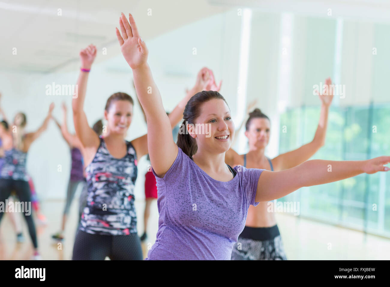 Smiling woman with arms raised in exercise class Stock Photo