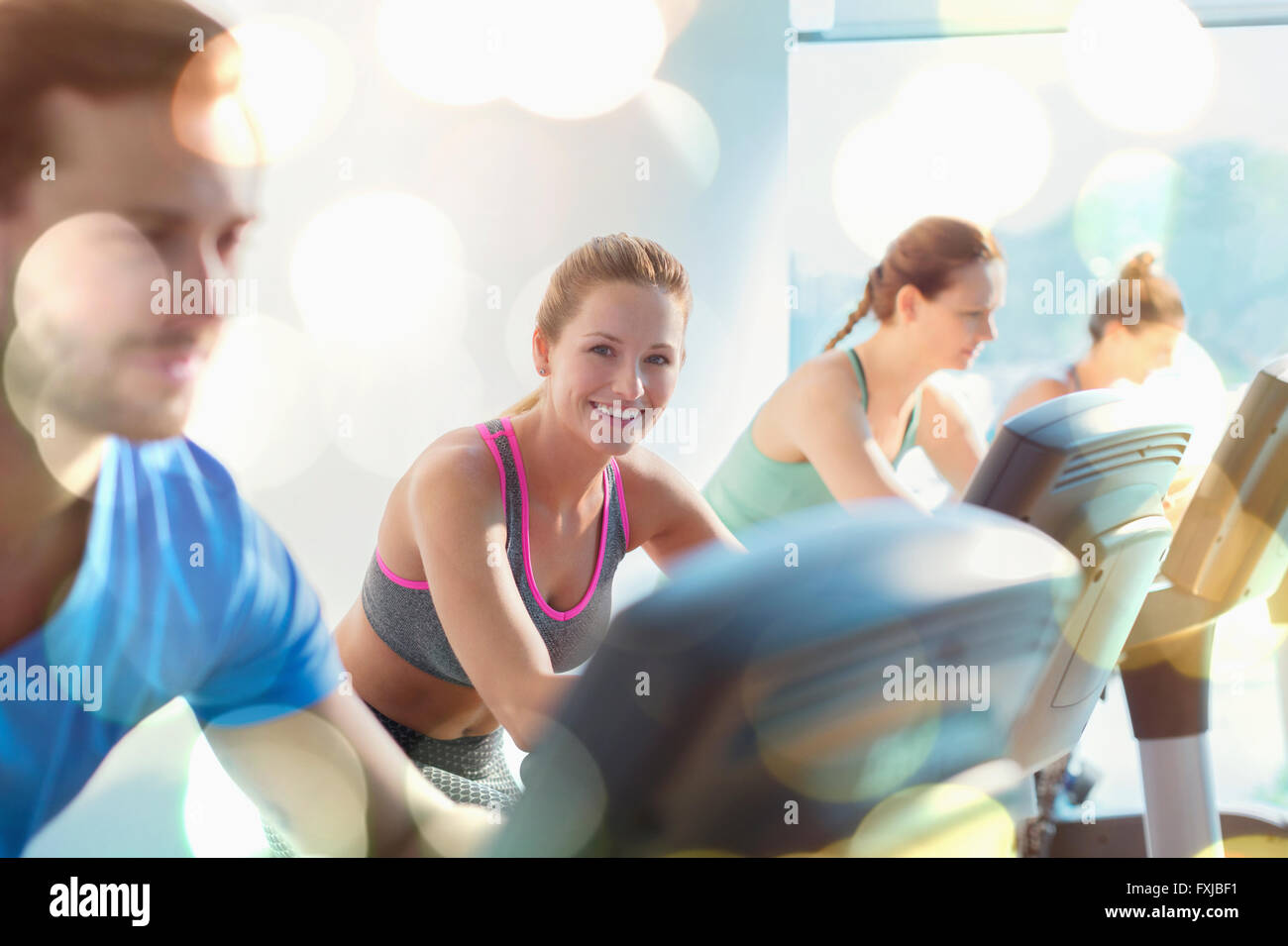 Smiling woman riding exercise bike at gym Stock Photo