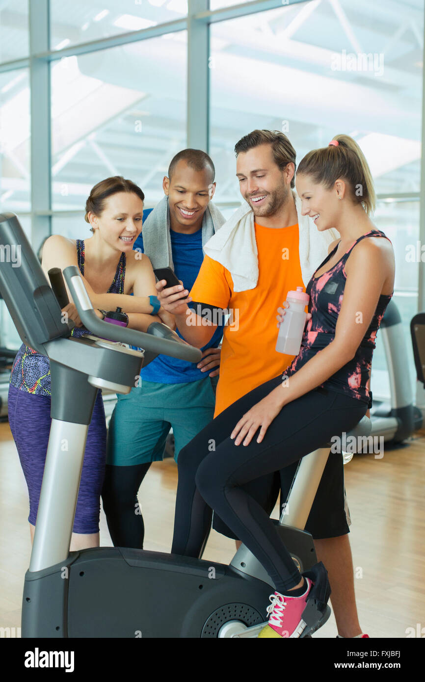 Friends using cell phone at exercise bike in gym Stock Photo