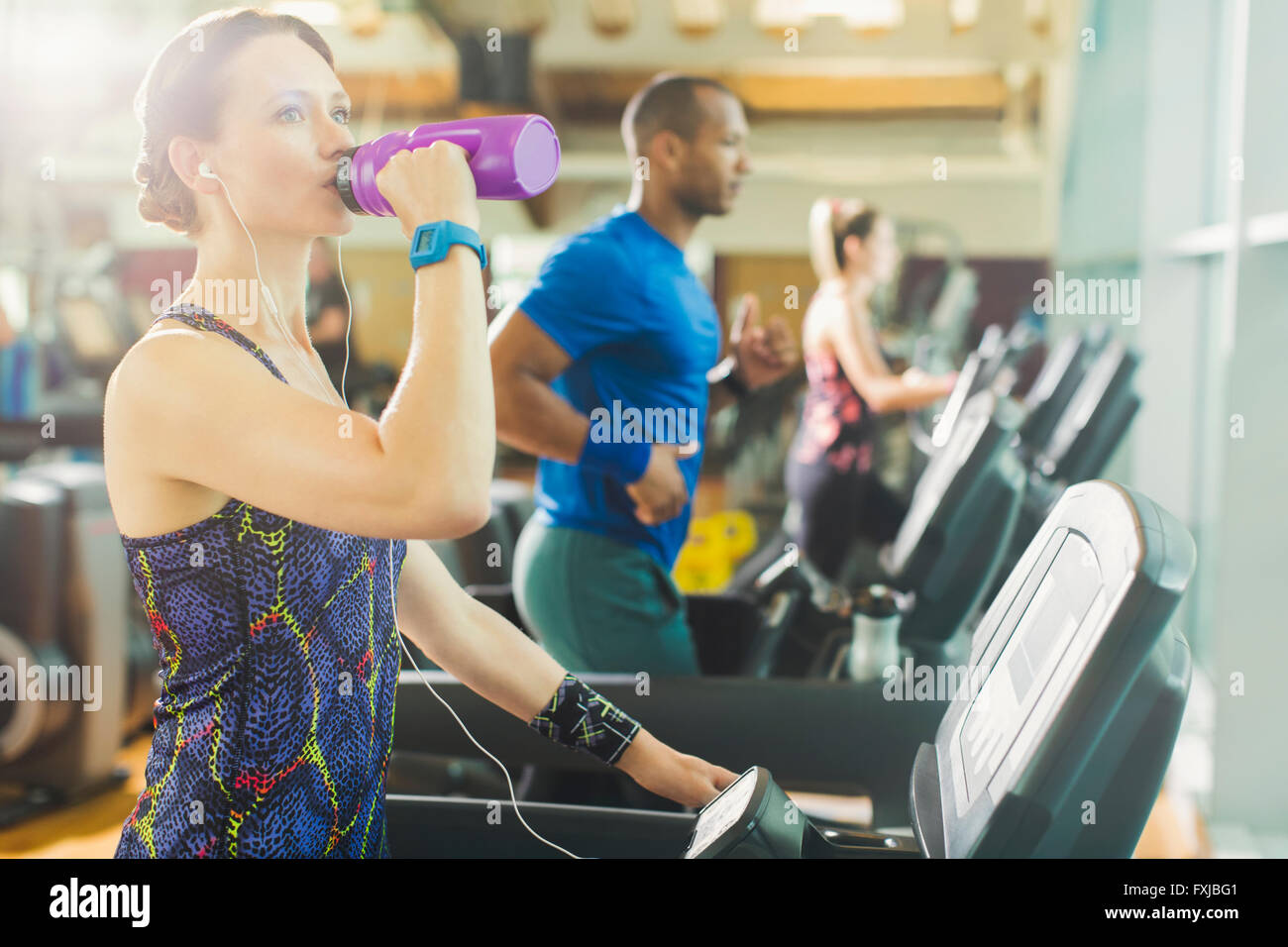 Woman on treadmill drinking water Stock Photo