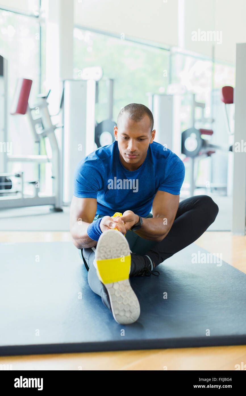 Man using resistance band to stretch leg at gym Stock Photo