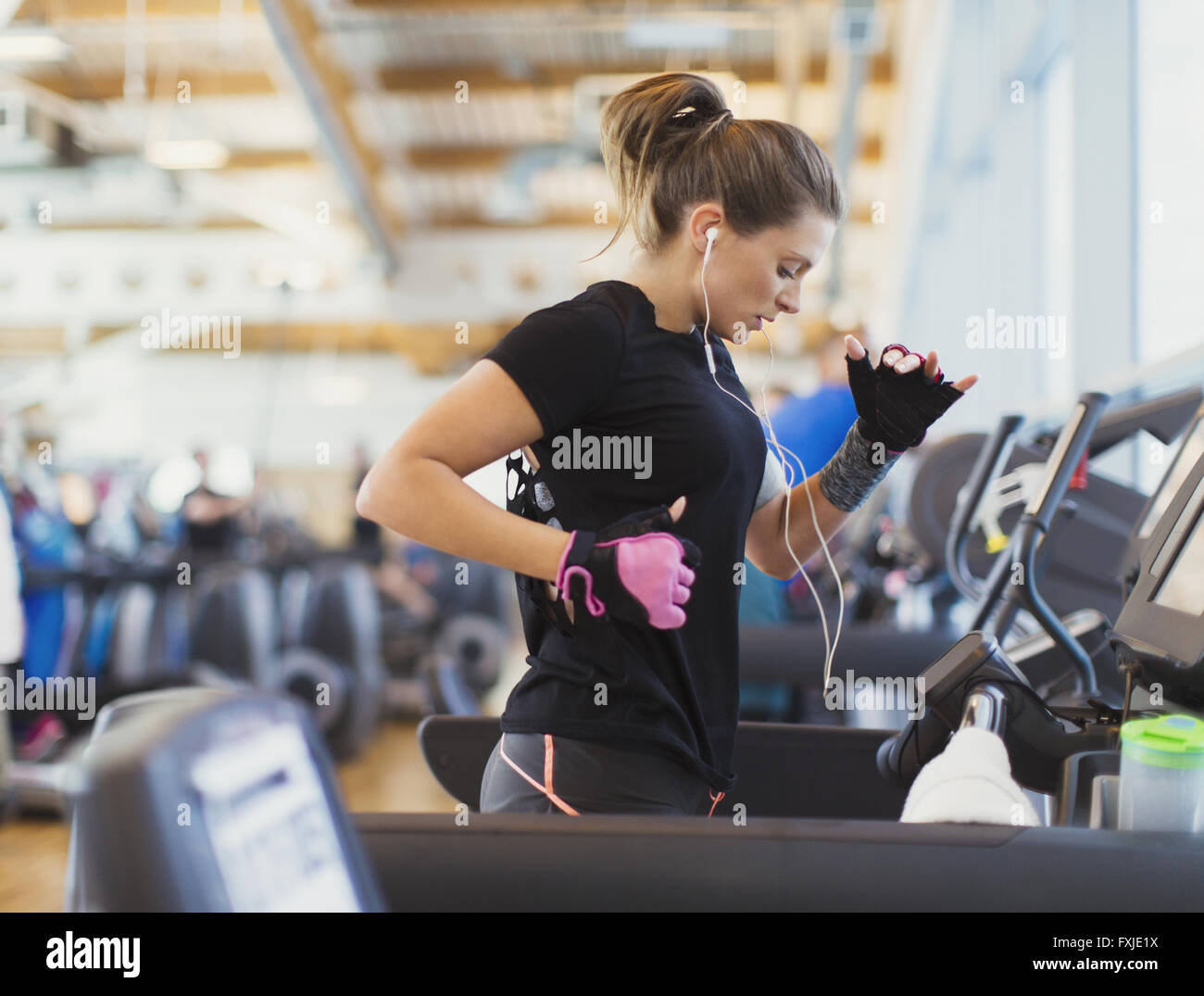 Woman running on treadmill at gym with headphones Stock Photo