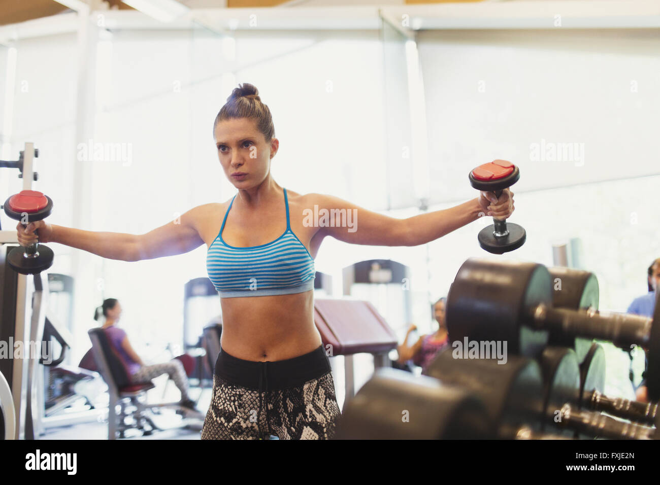 Focused woman doing dumbbell chest fly at gym Stock Photo