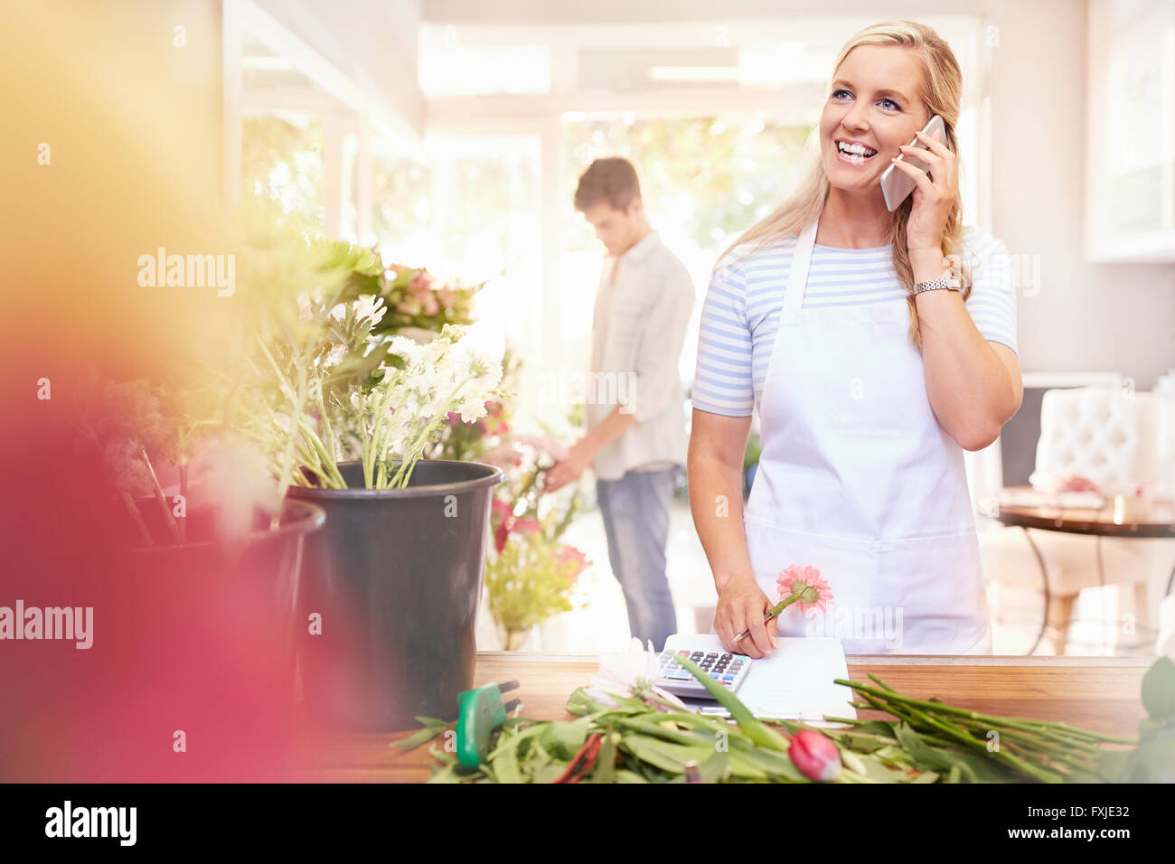 Smiling florist talking on cell phone in flower shop Stock Photo