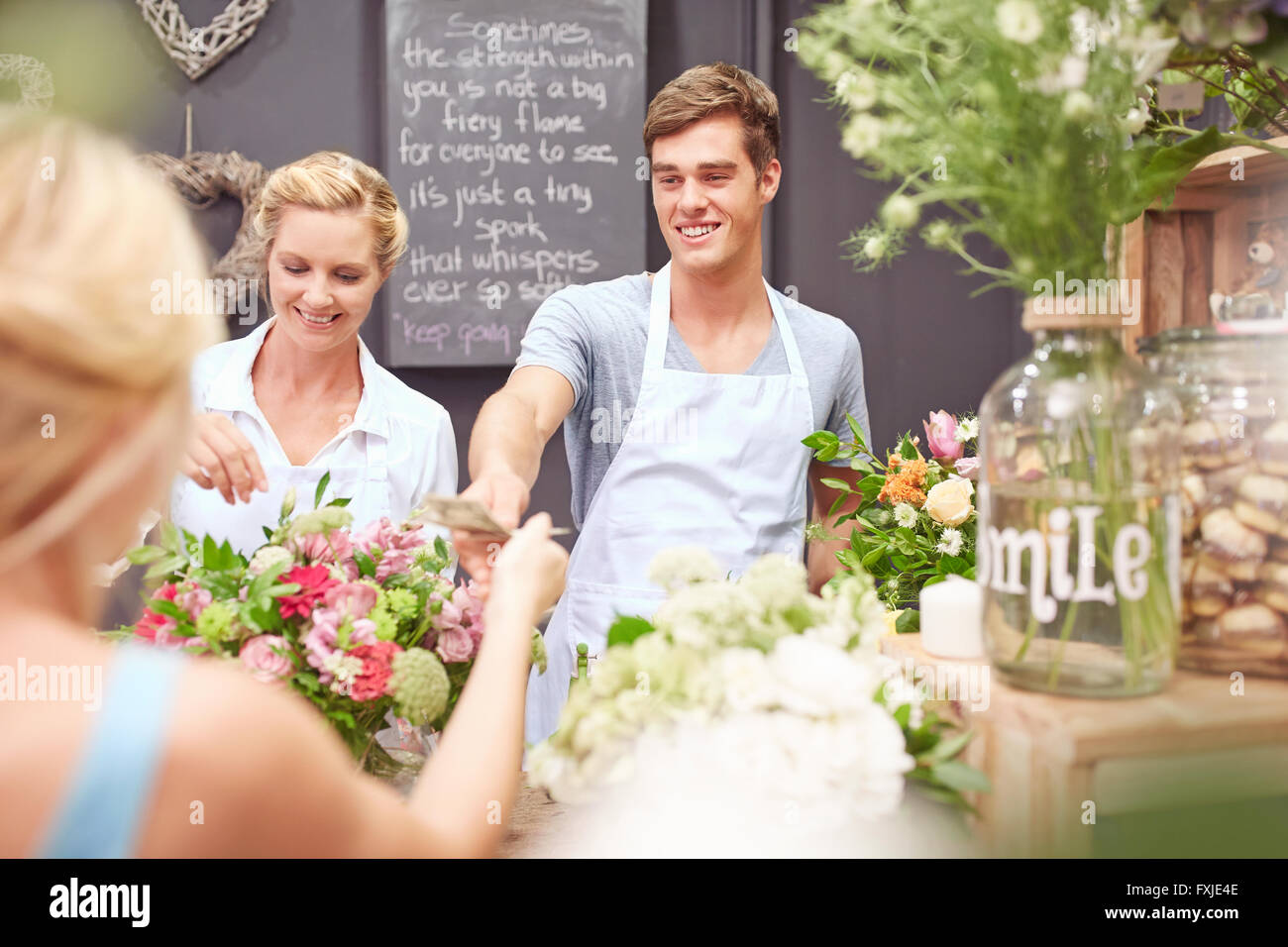 Florist taking money from woman in flower shop Stock Photo