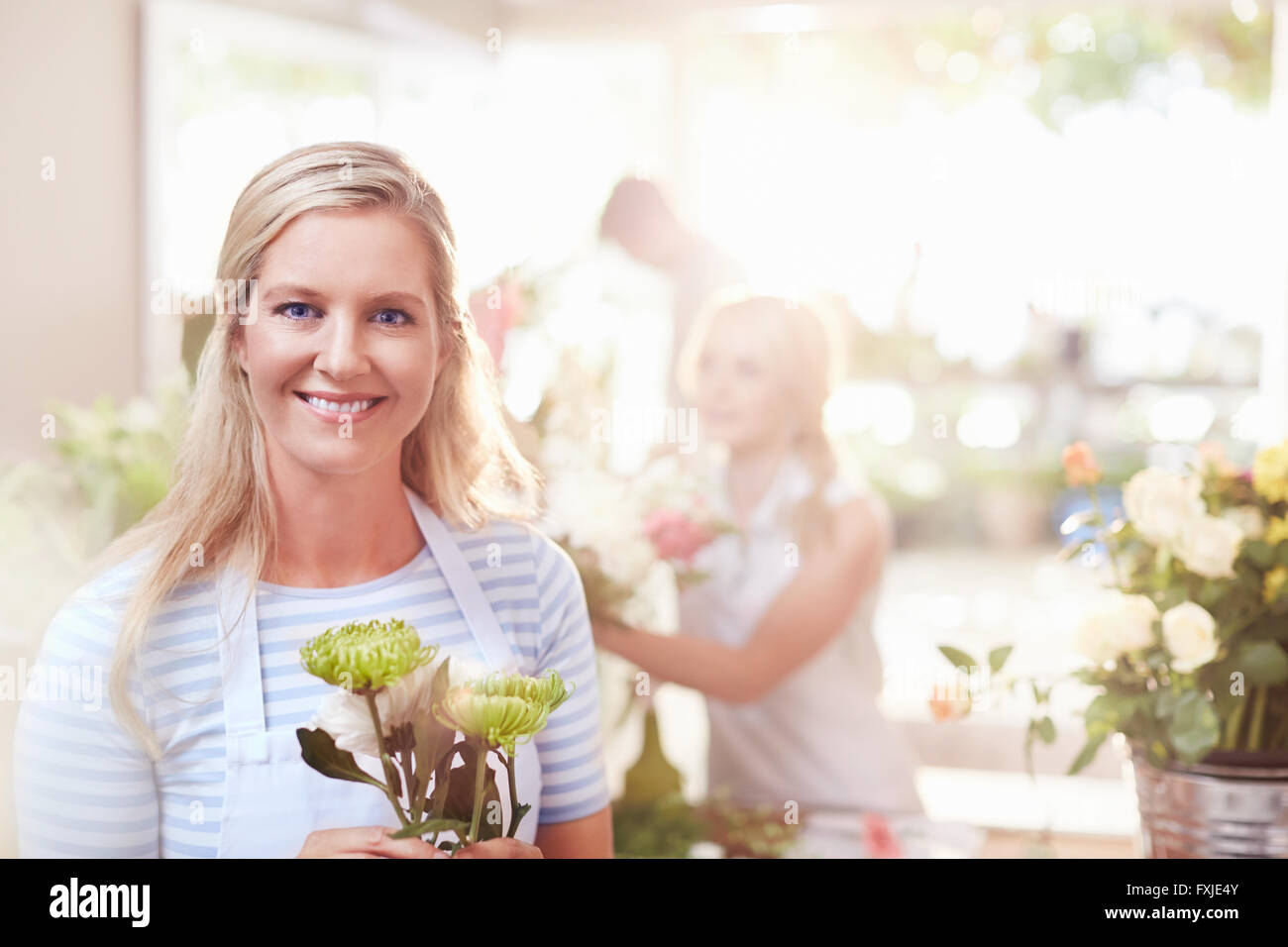 Portrait smiling florist holding spider mums in flower shop Stock Photo