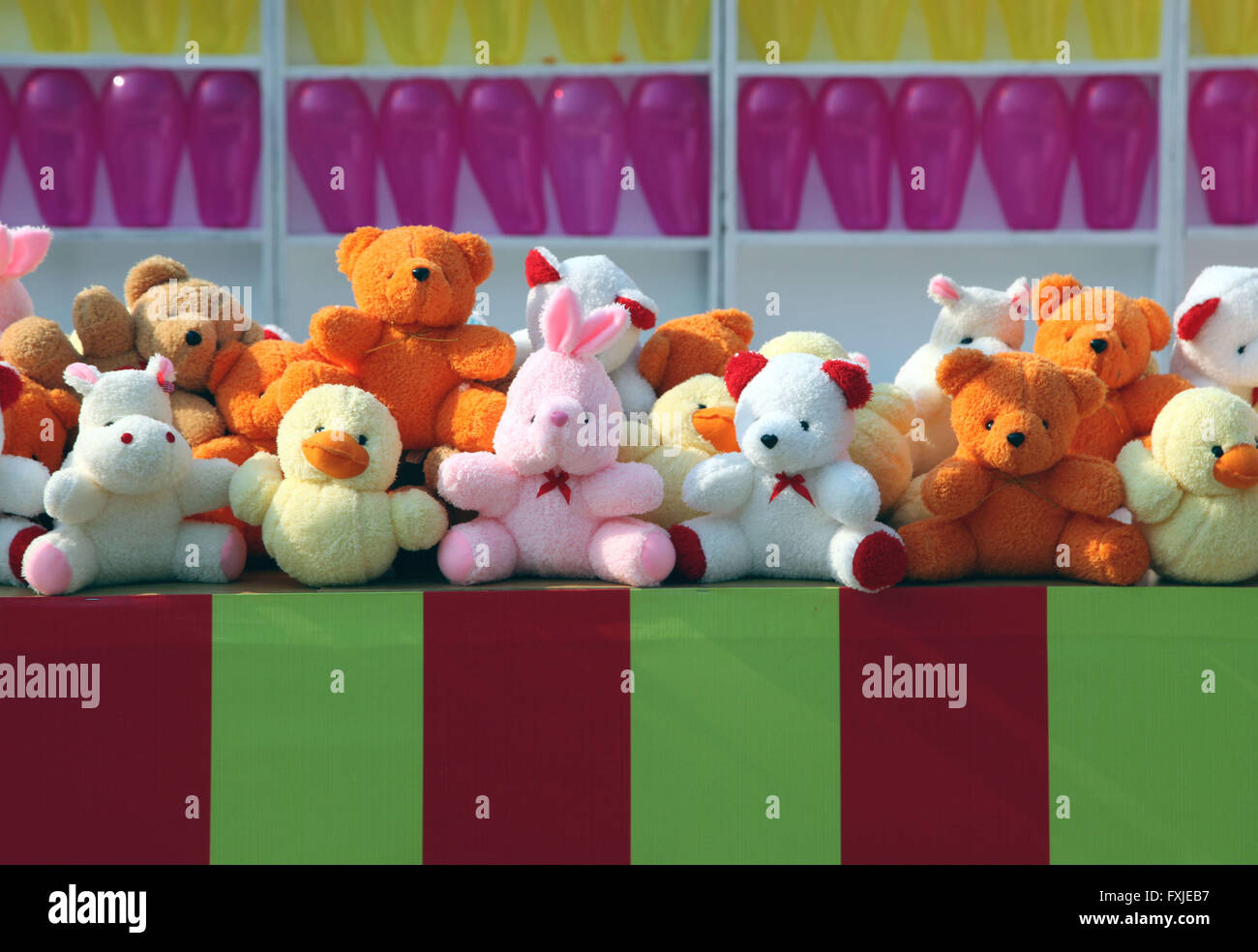 Many colorful balloons are side by side on a display. Fun fair game is call Pop the Balloon. We see fluffy prizes Stock Photo