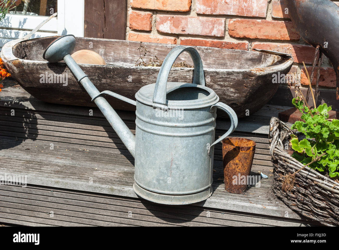 Old watering can and wooden kneading-trough as decoration in front of a house Stock Photo