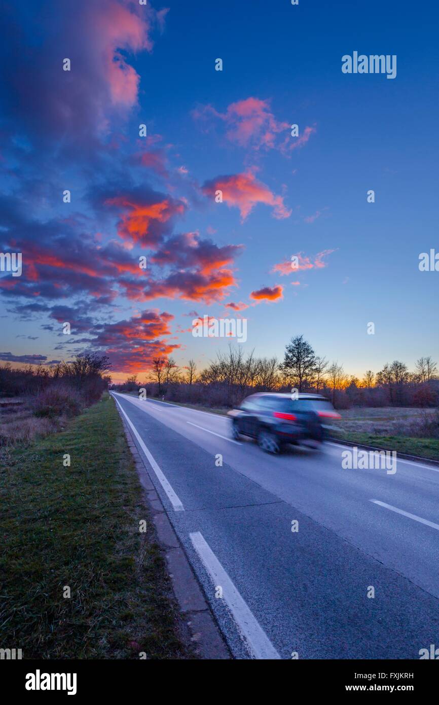 Sunset sky on road and speeding vehicle Stock Photo