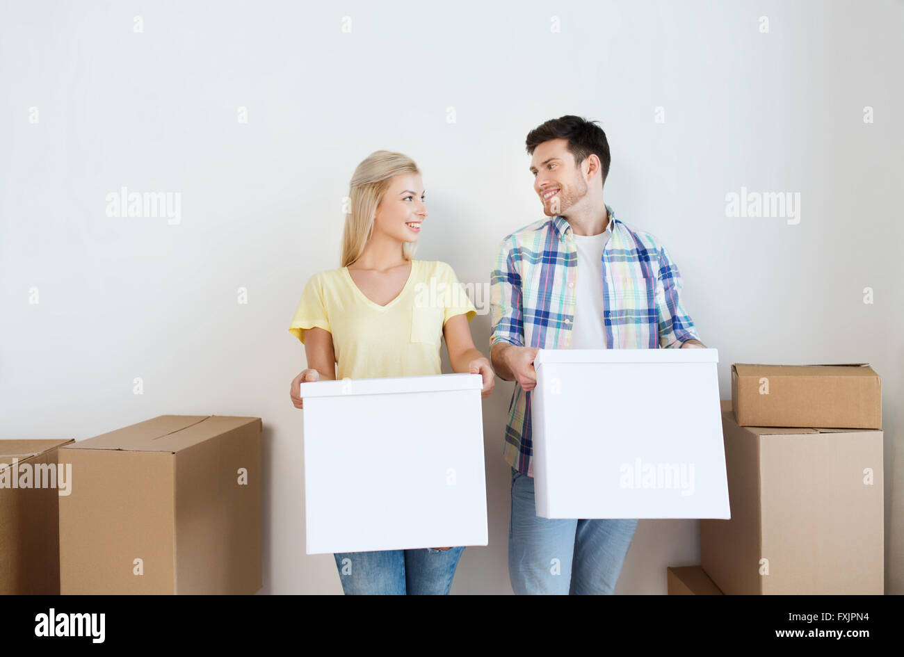 smiling couple with big boxes moving to new home Stock Photo - Alamy