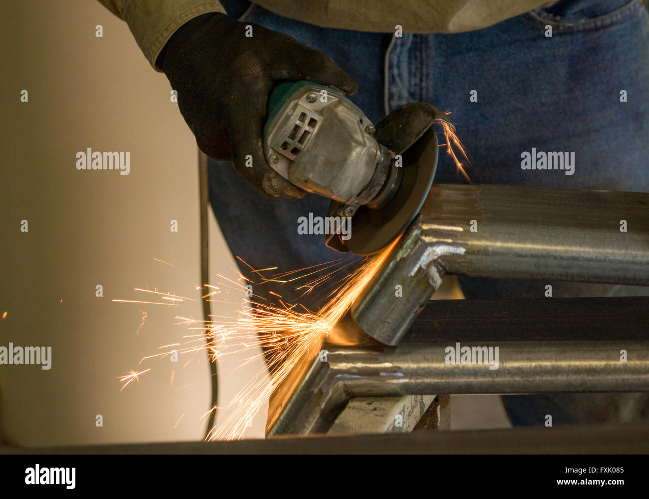 Man working with disc grinder after welding with sparks flying Stock