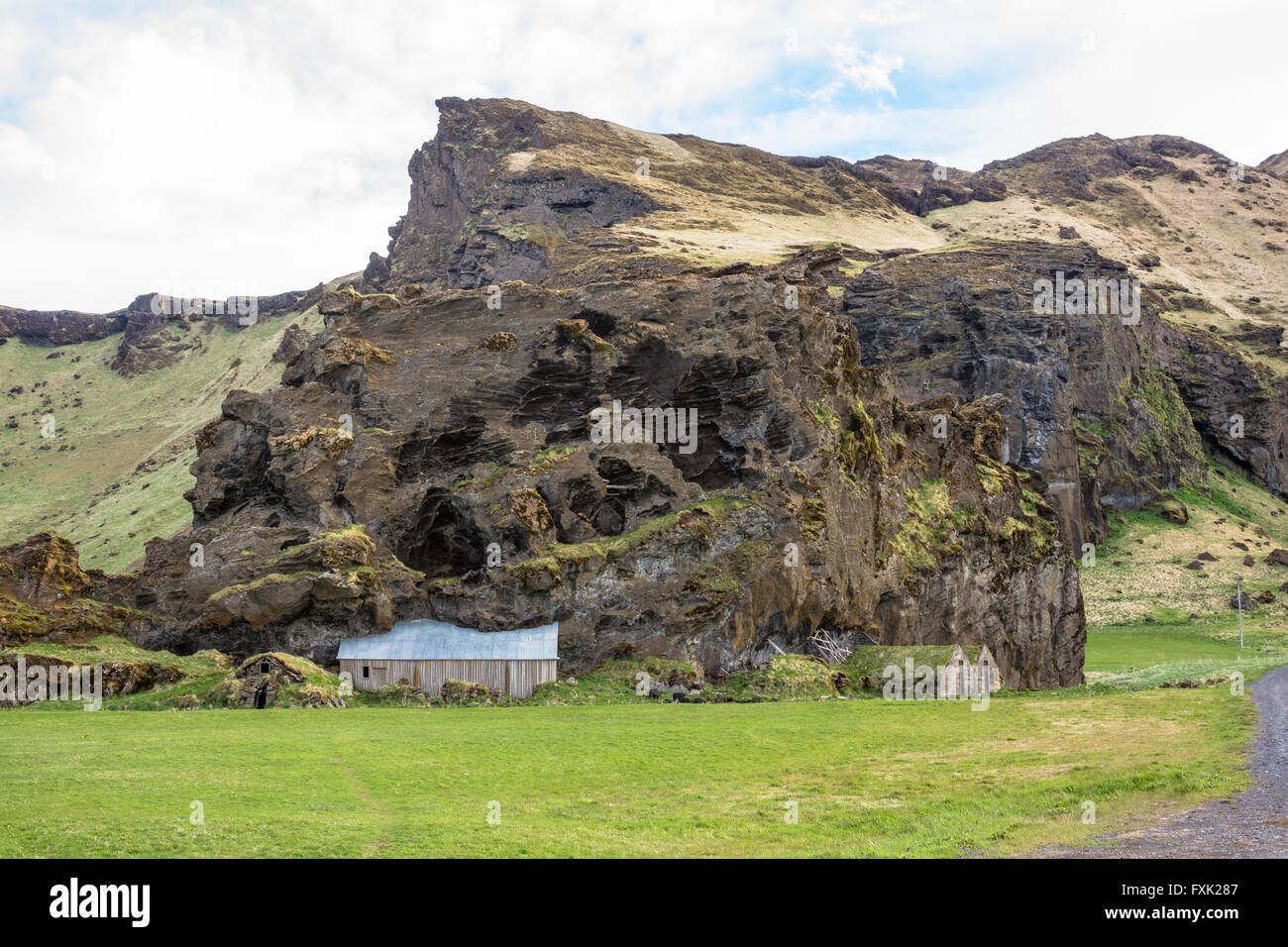 Volcanic rock mountain with turf houses on farmland in Iceland Stock Photo