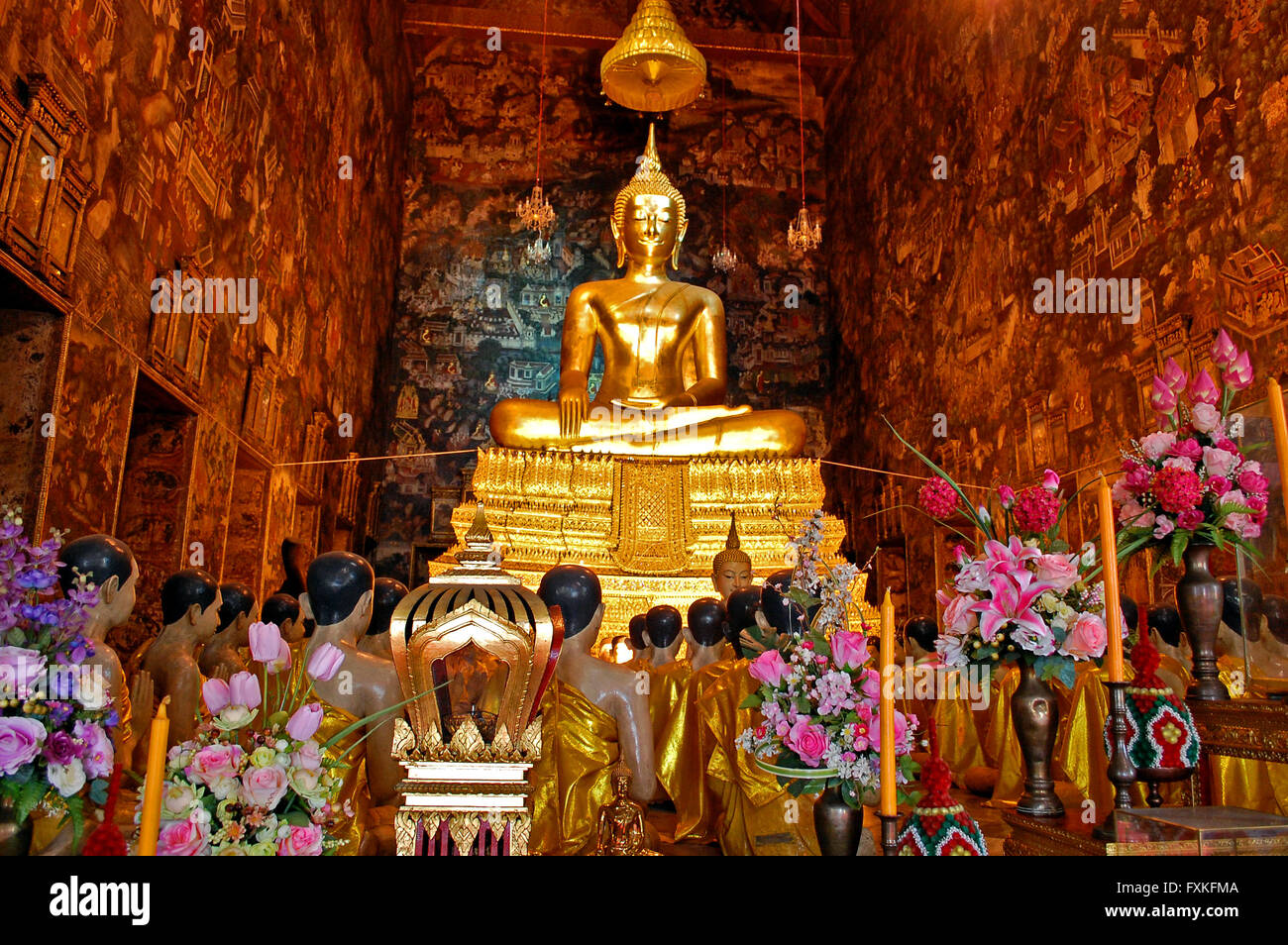 Large golden Buddha statue surrounded by statues of monks in prayer