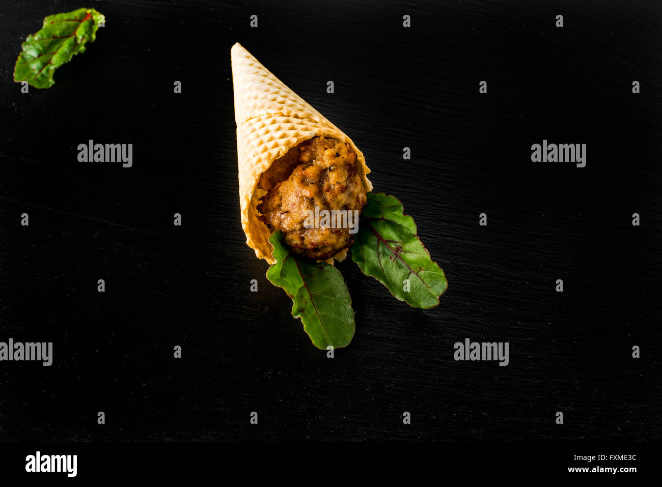 Meatball in a wafer cone on black slate tray Stock Photo