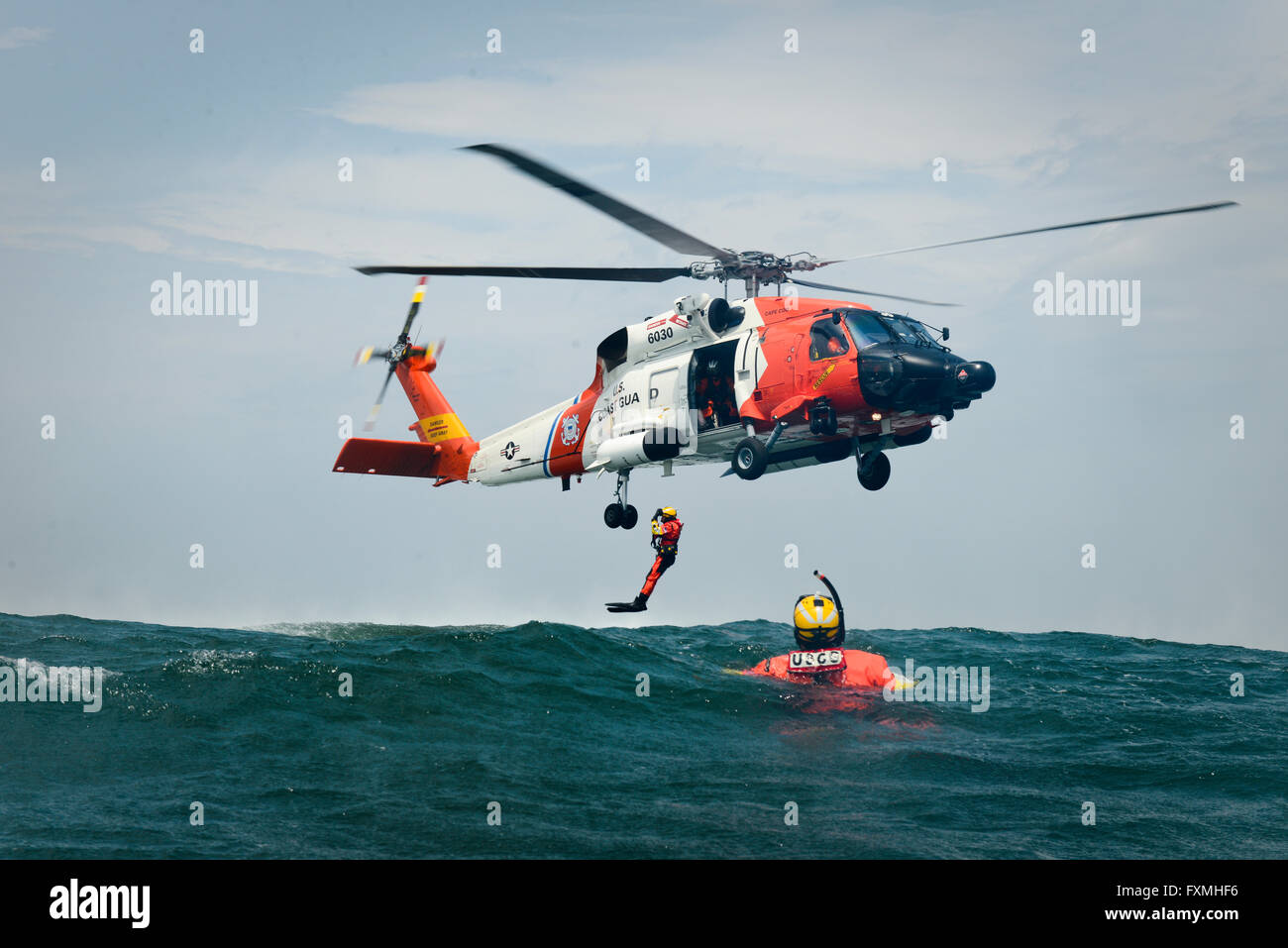 A US Coast Guard Rescue swimmers are deployed from a MH-60 Jayhawk Helicopter during rescue training in the Atlantic Ocean June 23, 2015 near Cape Cod, Massachusetts. Stock Photo