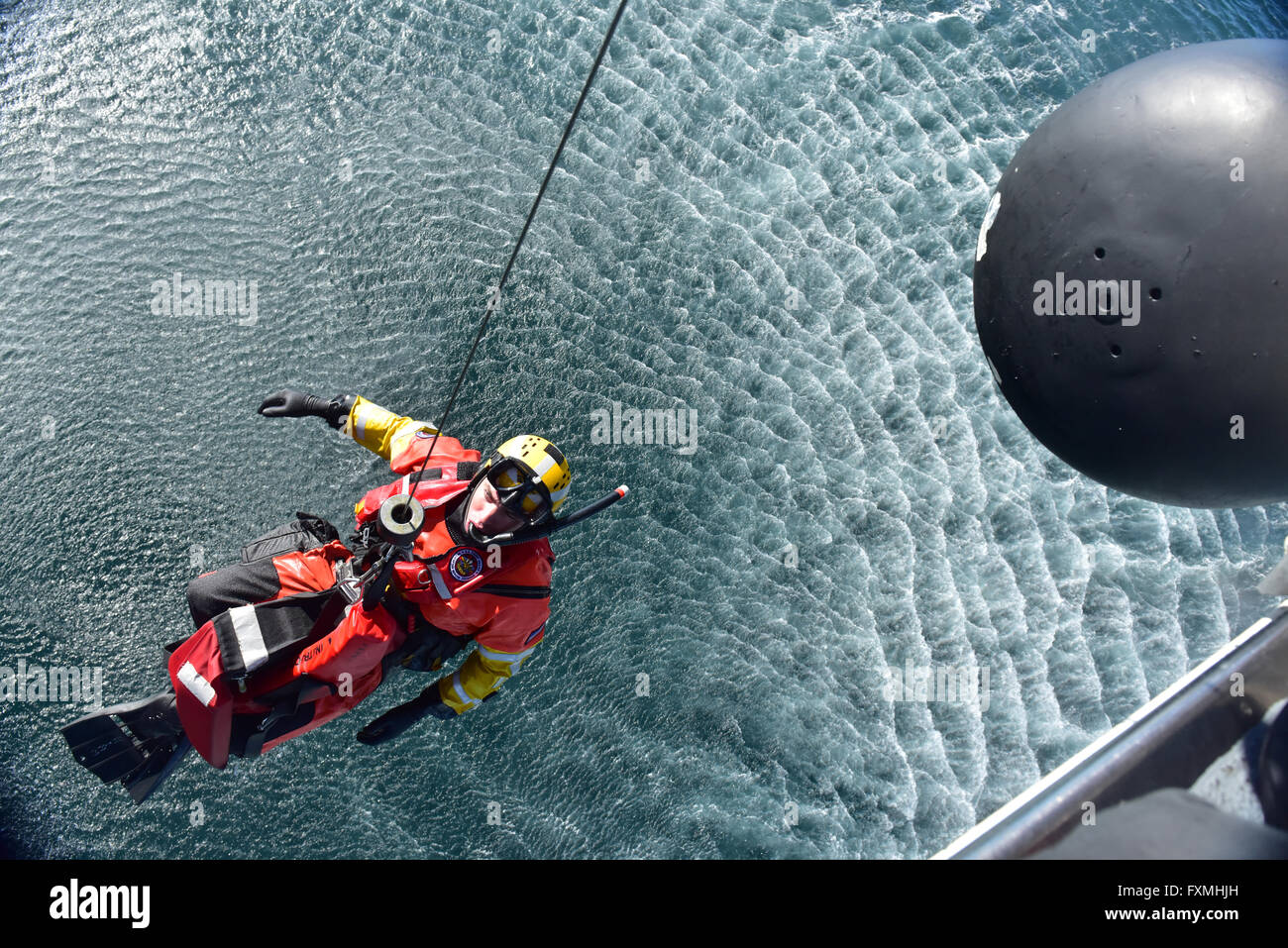 A US Coast Guard Rescue swimmer is hoisted from the water into a MH-60 Jayhawk Helicopter during rescue training in the Pacific Ocean January 12, 2016 near San Diego, California. Stock Photo