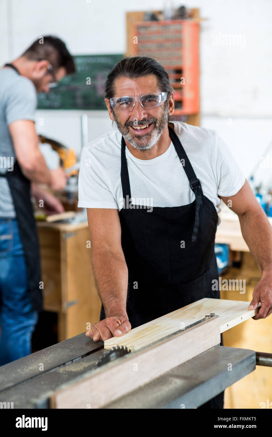 Carpenter using table saw for cutting wood at workbench Stock Photo