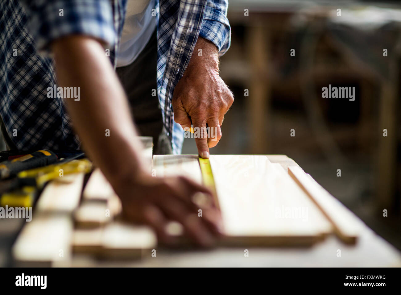 Carpenter measuring a length of wooden plank Stock Photo