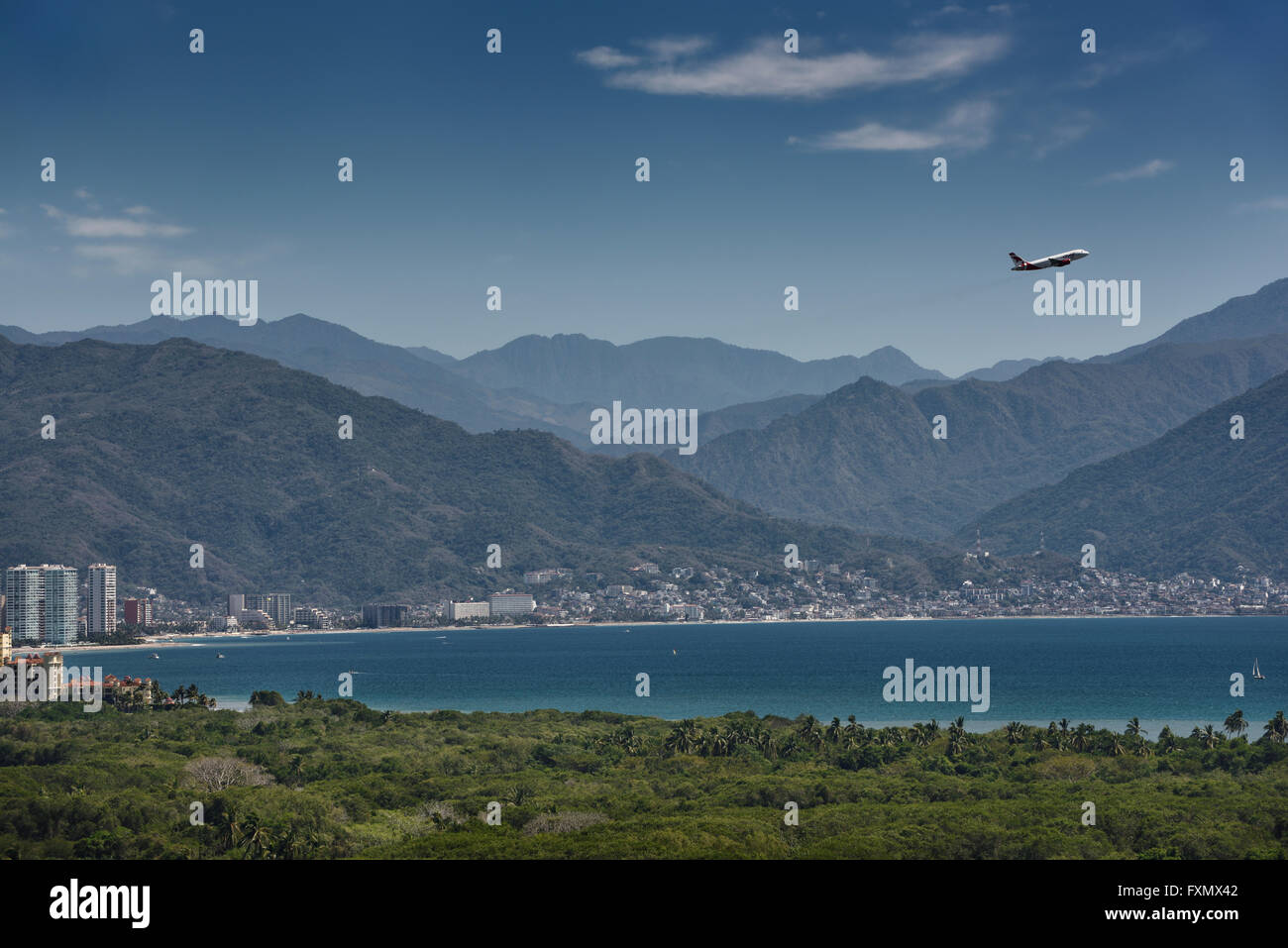 Jet aircraft taking off over Banderas Bay at Puerto Vallarta with Sierra Madre Mountains Stock Photo