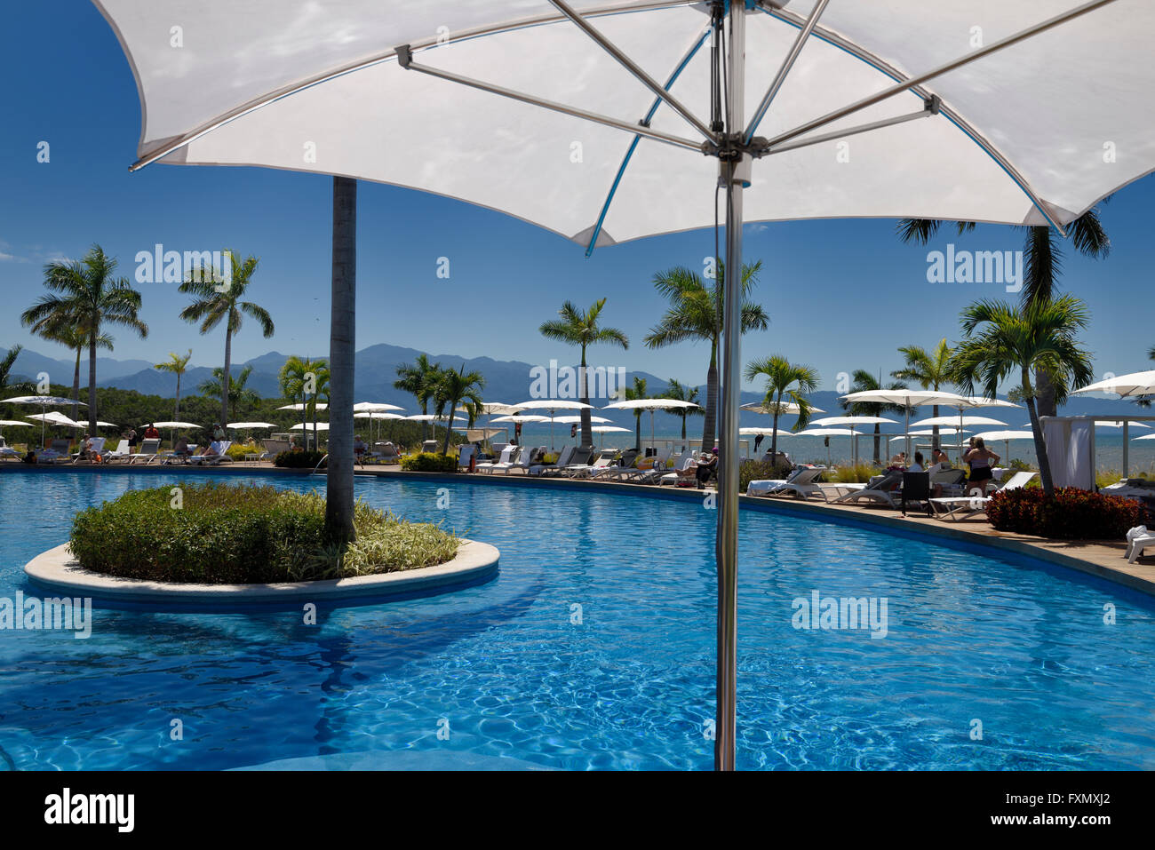 Under an umbrella poolside on the Pacific ocean with Sierra Madre mountains Mexico Stock Photo