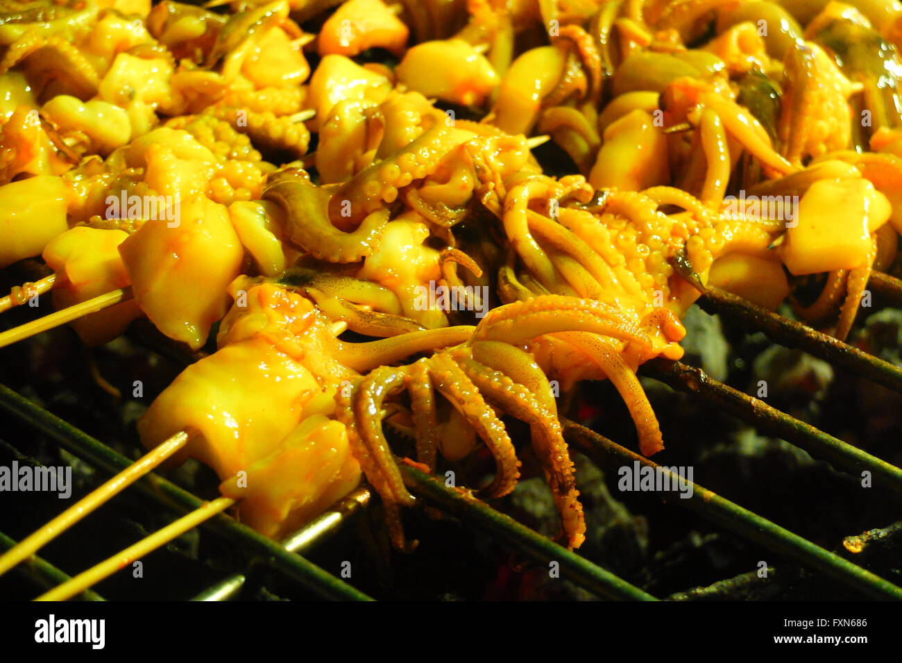 Asian style barbecued baby octopus on wooden skewers. Stock Photo