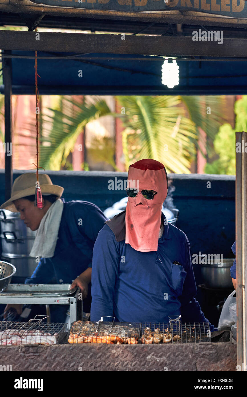 Face mask. Chef cooking at an outdoor market BBQ stall and wearing full
