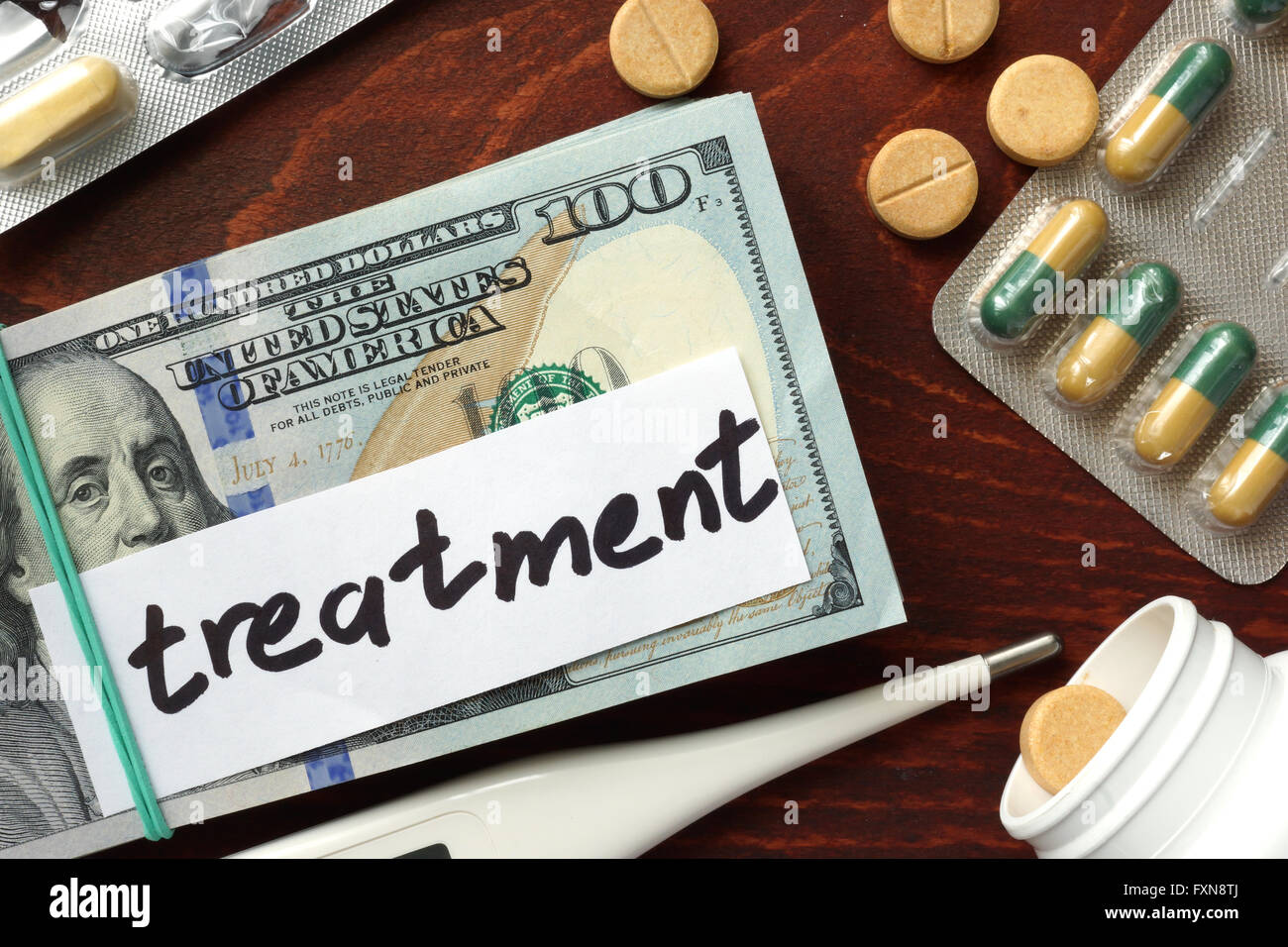 Dollars and pills on a wooden table. Treatment cost concept. Stock Photo