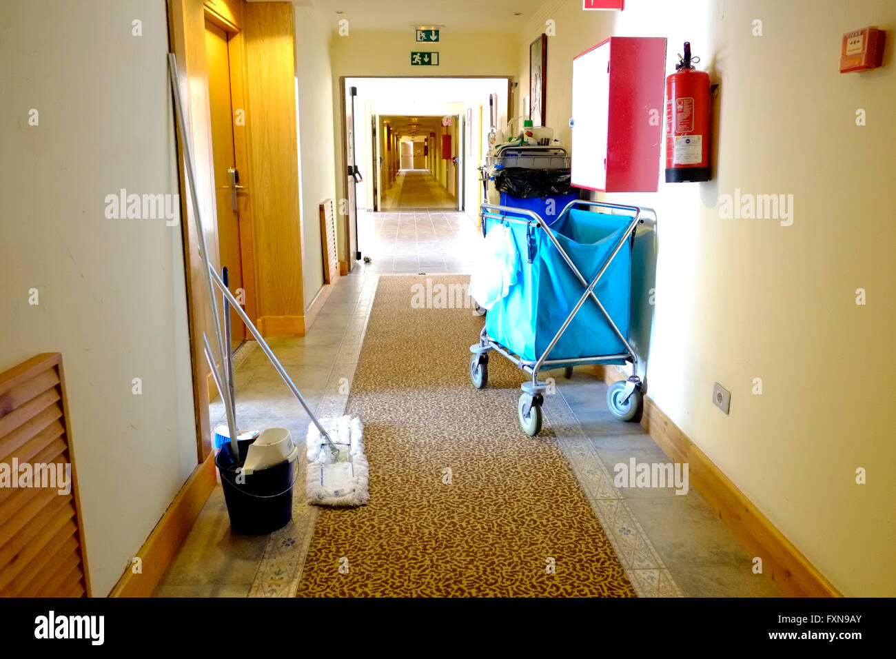 A hotel housekeeping cleaners trolley in a hotel corridor outside a guest room that's being cleaned. A laundry trolley is also being used by the team Stock Photo