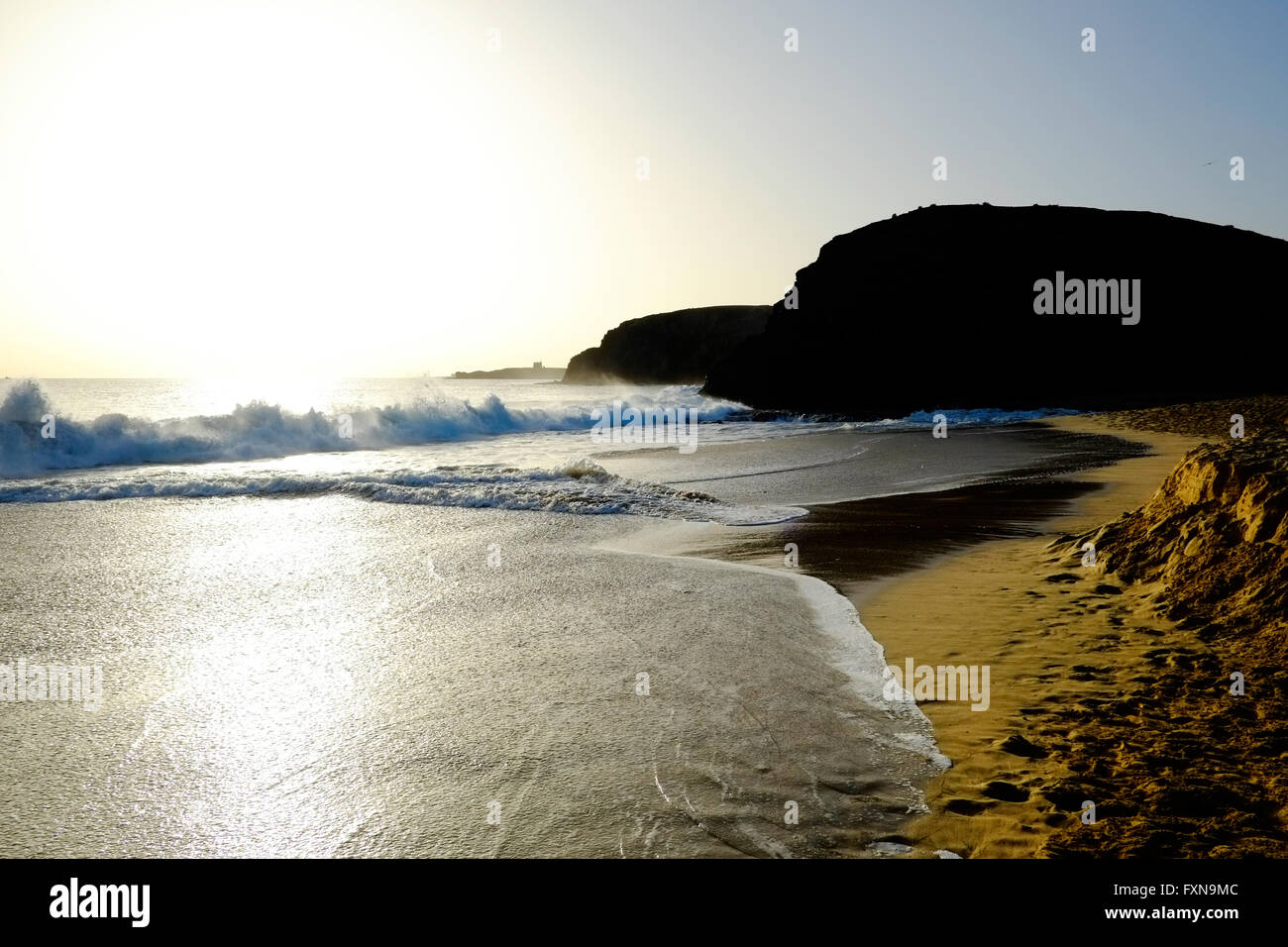 Waves crash onto the shore line as the sun sets over Papagayo beach, Lanzarote Stock Photo