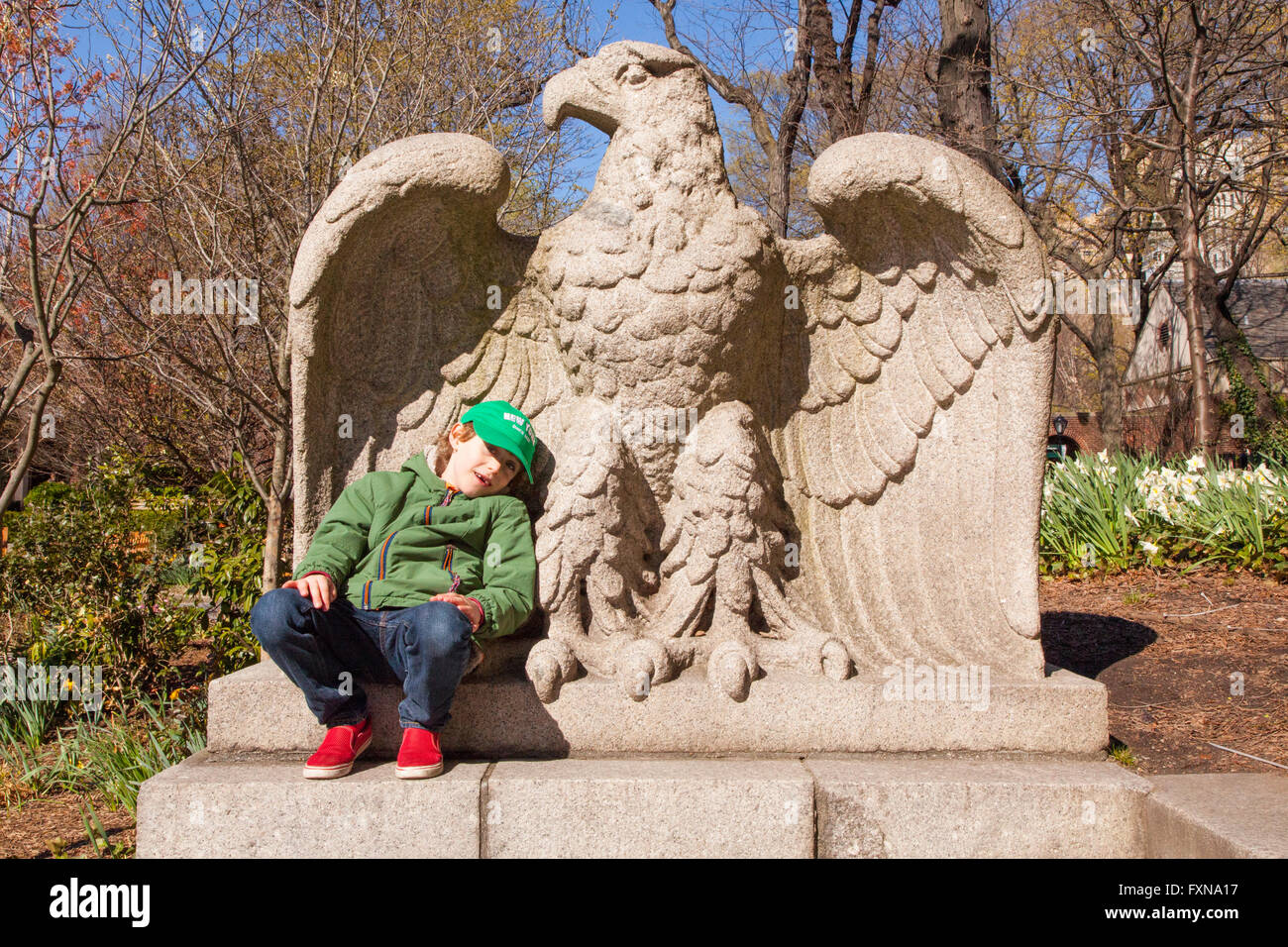 Boy resting on a giant stone eagle 