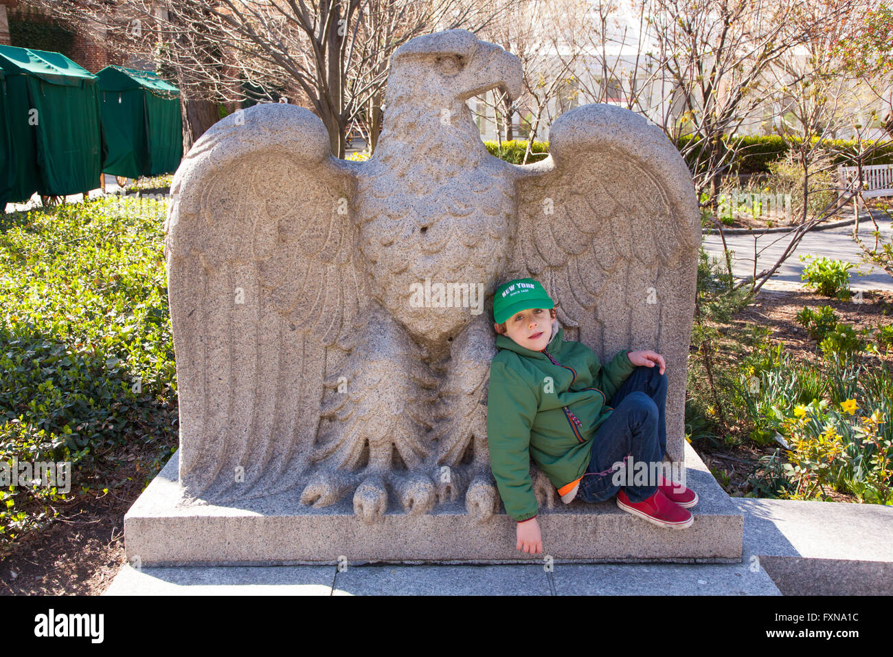 Boy resting on a giant stone eagle, Central park Zoo, Manhattan, New