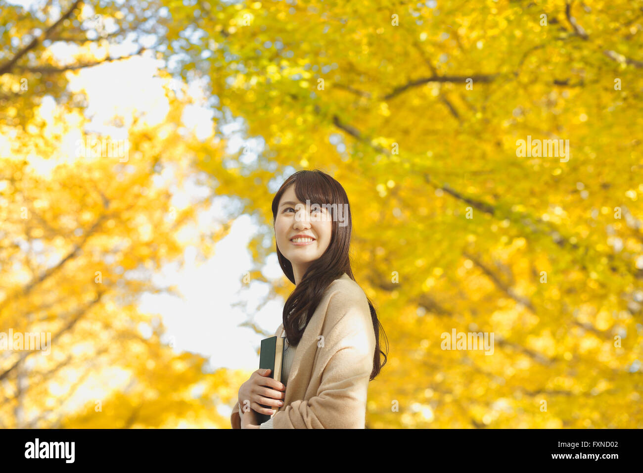 Young Japanese woman with book in a city park Stock Photo