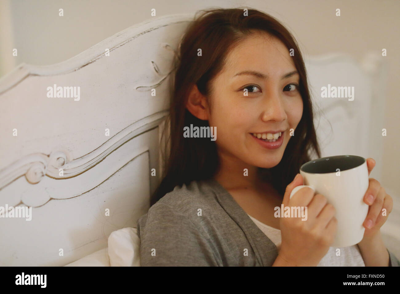 Young attractive Japanese woman drinking coffee in bed Stock Photo Alamy