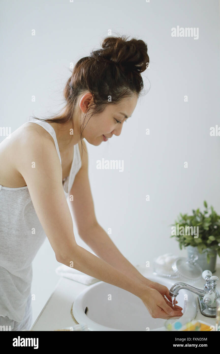 Young attractive Japanese woman washing face in the bathroom Stock
